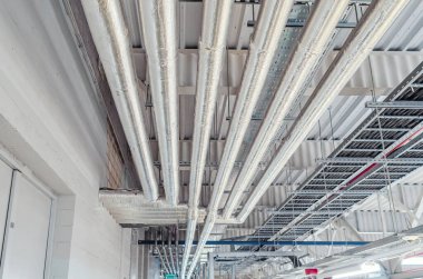 Tavan altına monte edilmiş metal borular modern üretim tesisinde termal yalıtım ile kaplıdır.