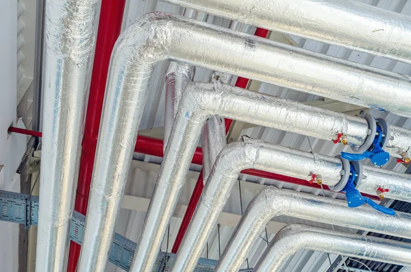 Tavan altına monte edilmiş metal borular modern üretim tesisinde termal yalıtım ile kaplıdır.