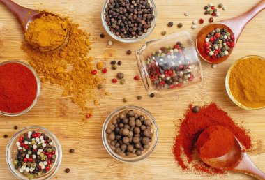 Ahşap kaşıklarda çeşitli baharatlar ve ahşap arka planda şeffaf kaseler. Yemek blogları, yemek tarifi tasarımı, gurme yemekleri, organik ürünler için mükemmel. Aşçılık ilhamı.