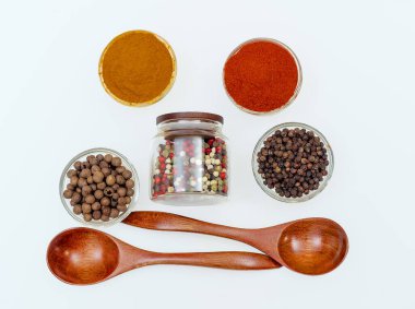 Şeffaf küçük kaselerde çeşitli aromatik baharatlar ve baharatlar ve beyaz arka planda ahşap kaşıklar. Web sitesi, yemek ekran koruyucuları için kullan.