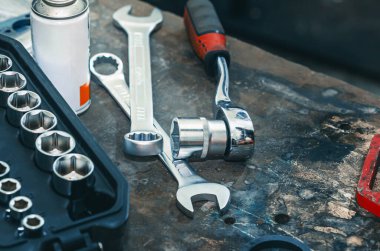 Masanın arka planında soket anahtarı ve yapıştırıcıyla tamir mekanizmaları var. Siyah çantada profesyonel aletler. Tamir masası.