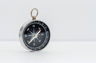 Siyah kadranlı klasik pusula beyaz arkaplanda izole edilmiş. Oklu navigasyon cihazı kardinal kuzey, güney, doğu ve batıyı gösteriyor. Metal kutu. Boşluğu kopyala.