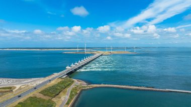 Bulutlu gökyüzünün altındaki yel değirmenlerinin drone görüntüsü. Hollanda 'da. Sürdürülebilir kalkınma, yenilenebilir enerji, elektrik üretiminde yeni teknolojiler. Rüzgar santrali.