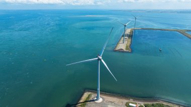 Bulutlu gökyüzünün altındaki yel değirmenlerinin drone görüntüsü. Sürdürülebilir kalkınma, yenilenebilir enerji, elektrik üretiminde yeni teknolojiler. Rüzgar santrali. Hollanda.