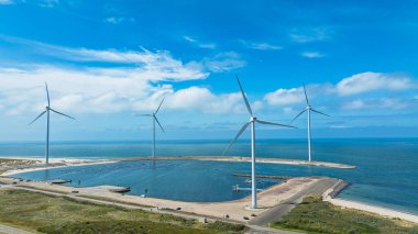 Bulutlu gökyüzünün altındaki yel değirmenlerinin drone görüntüsü. Sürdürülebilir kalkınma, yenilenebilir enerji, elektrik üretiminde yeni teknolojiler. Rüzgar santrali. Hollanda.