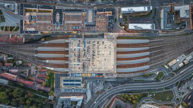 Akşam karanlığında Krakow 'un ana istasyonunun hava görüntüsü aydınlanmış platformları, çatıları ve dinamik şehir altyapısını gösteriyor..