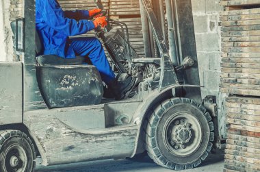 Endüstriyel depoda forklift kullanan kendinden emin bir kadın. Ağır sanayide kadınların güçlendirilmesi, profesyonellik ve cinsiyet kalıplarının kırılması kavramı.