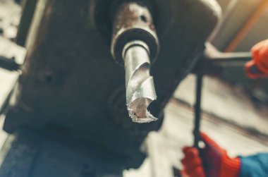 Fabrikanın içindeki üretim makinesinden çıkan büyük metal endüstriyel matkabın düşük açılı görüntüsü. Ağır sanayi, metal işçiliği, endüstriyel ekipman kavramı.