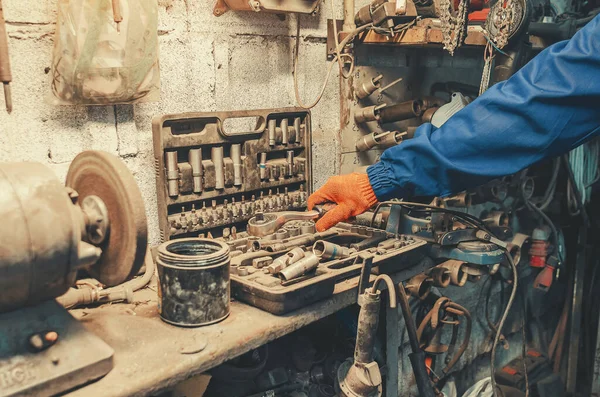 Klasik mekanik tamir atölyesinin arka planına yakın plan el ele tutuşmalar. Geleneksel işçilik, el işi ve klasik endüstriyel aletler..