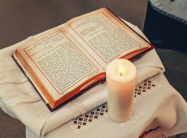 Yanan mum, Hristiyan inancı, duası, ibadeti ve ruhani yansıması olan beyaz sunak örtüsü üzerine açık İncil..