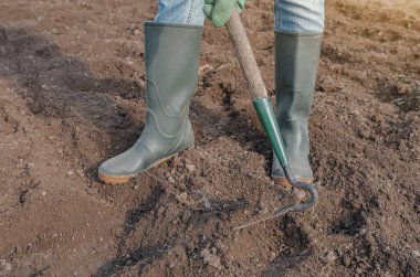 Toprağı şekillendiren botlar ve el aletleri, iş projesine veya uzun vadeli yatırıma başlamadan önce zemin, hazırlık ve disiplin çabalarını sembolize eder.