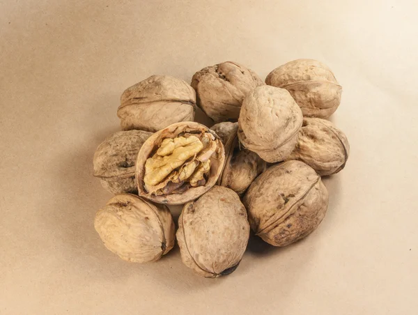 Walnut kernels and whole walnuts on kraft paperf, close up — Stock Photo, Image