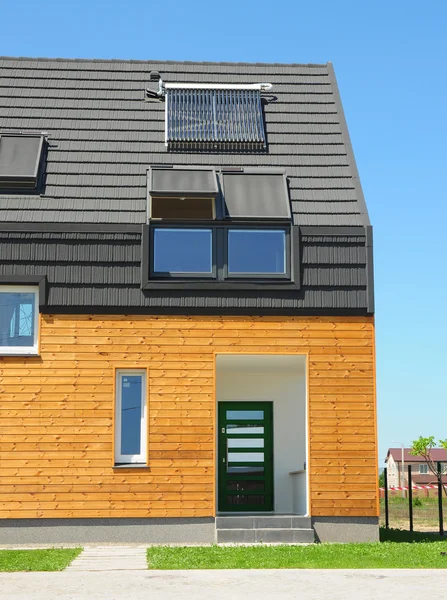 Casa moderna com conceito de solução de eficiência energética ao ar livre. Nova casa de construção de energia solar, aquecedor de água solar, painéis solares, clarabóias, instalado no telhado telhas de asfalto — Fotografia de Stock