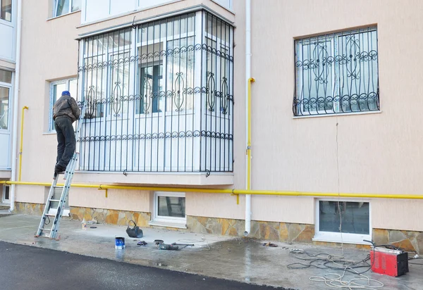 Contratista instalando barras de seguridad de hierro ventana. Barras de seguridad para ventanas y balcón — Foto de Stock