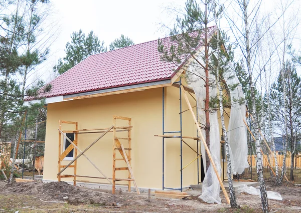 Закрыть на картине и штукатурке стены внешнего дома. Строительство дома с металлической крышей в лесу . — стоковое фото