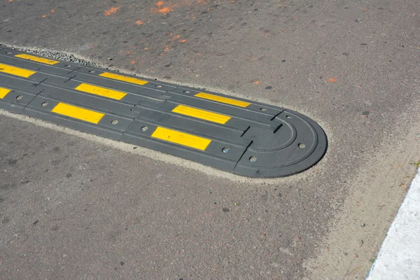 Traffic safety speed bump on an asphalt road. Speed bumps (or speed breakers) are the common name for a family of traffic calming devices.