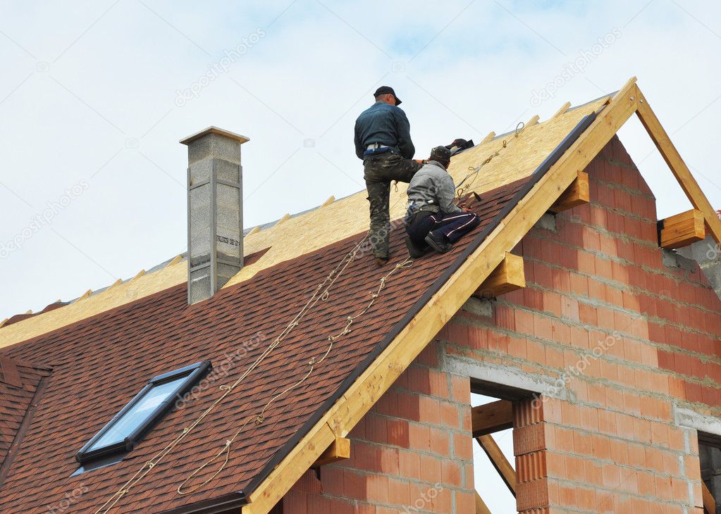 Roofers laying tiles on the roof while roofing a house outdoor. Roofers Install, Repair Asphalt Shingles or Bitumen Tiles on the Rooftop 