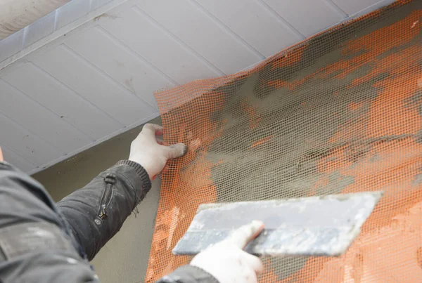一个建筑承包商正在安装一个加固网 并将屋檐下的房屋的外墙隔离起来 — 图库照片