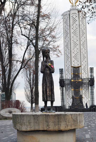 KYIV, UKRAINE - November 06, 2020: A statue of a young girl known as The Bitter Memory of Childhood in Memorial in Commemoration of the Holodomor Genocide in Ukraine with The Candle of Memory monument