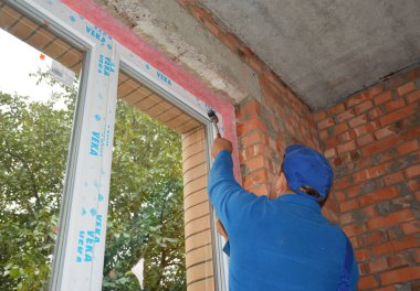 KYIV, UKRAINE - 26 Ekim 2020: Bir profesyonel, yumuşak başlı çekiç kullanarak kuşağın tabanına cam paneller yerleştirip çerçevenin içine cam paneller yerleştiriyor.
