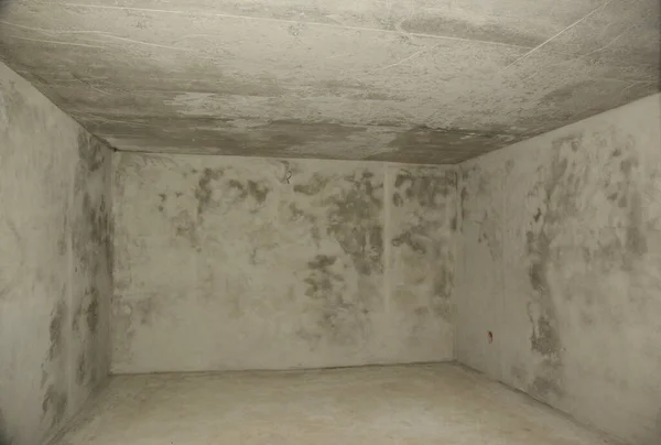 A view of an empty concrete rendered underground basement, cellar, bombproof shelter or nuclear fallout shelter.