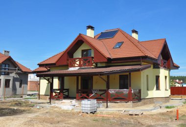 Yıldırım koruması ve kil kiremitleri, paratoner, veranda, sıva duvarları, tavan penceresi ve güneş suyu ısıtma paneli olan karmaşık çapraz geçişli, enerji tasarruflu bir ev inşa etmek..