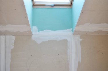 Tavan arası penceresinin etrafına alçıtaşı alçıpan döşemesi. Oda yenileme sırasında dikişleri doldurmak için kaygan bir bileşik kaplaması uygulanıyor..