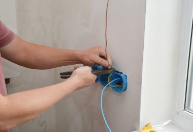 Bir elektrikçi yeni bir priz kuruyor, plastik elektrik kutularına kablolar döşeyerek çoklu priz soketi.. 