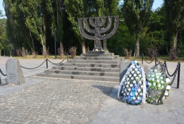 KYIV, UKRAINE - SEPTEMBER, 29, 2020: A menorah memorial with floral tribute to commemorate jewish victims of Holocaust located in Babi Yar, Kyiv. clipart