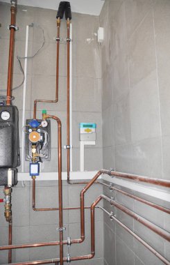 Kazan dairesinde bakır borular, bakır borular, ısı pompası ve kontrol paneli olan ısıtma sistemi..