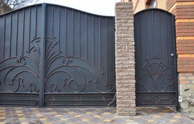 Evin yakınındaki siyah metal dövmeli demir kapı ve çelik çite yakın çekim. Demir çit süsü satmış..  