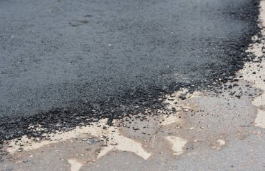 Yoldaki çukur onarımının yakın çekimi, tamir edilmiş asfalt yol. Asfaltta eski ve yeni asfalt. 