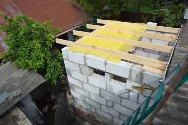 Otoklavize edilmiş beton bloklardan ev yapımı. Evin tuğla duvarlarının üzerine ahşap kirişler ve buhar bariyeri yerleştiriliyor.. 