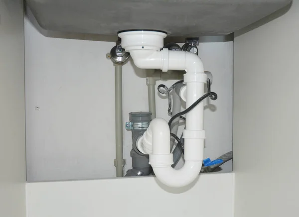 Kitchen renovation and plumbing: Replacing and installing kitchen sink PVC drain pipes, sink trap pipes under a kitchen sink.