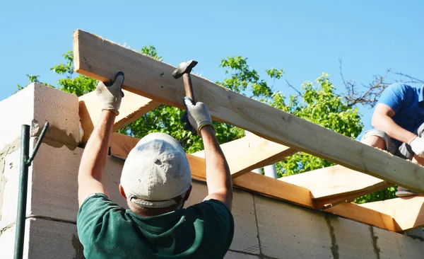 Roofing construction. Roofing contractors are wood framing the roof installing roof rafters and boards using hammers and nails.