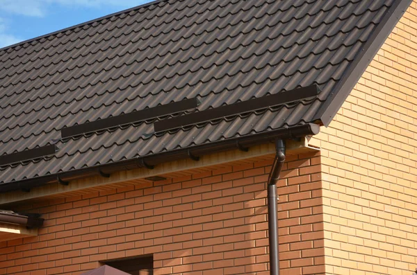 Zbliżenie Metalowym Brązowym Dachu Murowanego Domu Korkami Śnieżnymi Strażnikami Śnieżnymi — Zdjęcie stockowe