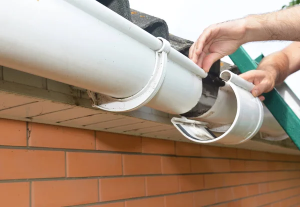 屋顶排水沟的安装和维修 梯子上的一个人正在更换塑料雨槽接缝 将雨槽连接起来 — 图库照片