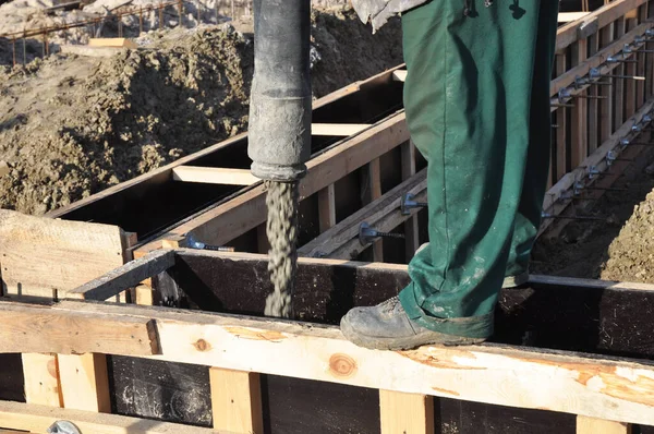 混凝土基座的建造 一个建筑承包商正在把一块混凝土板浇注到一个木材混凝土模板中 作为一座新房子的混凝土地基 — 图库照片