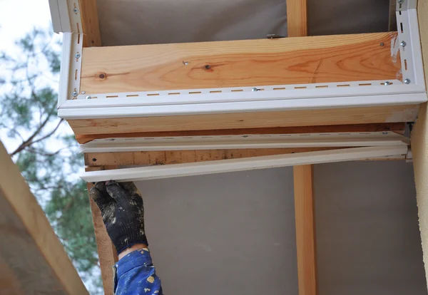 O trabalhador do telhado usa uma mão para instalar soffit, beirados, vigas de madeira. Telhado casa nova — Fotografia de Stock