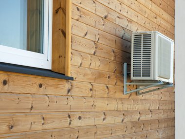 Air conditioner condenser on the wooden wall of boards. clipart