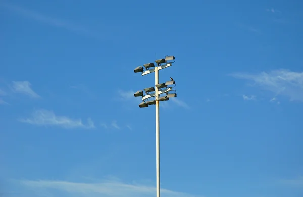 Stadium lights with bird against blues sky and white clouds — Stock Photo, Image
