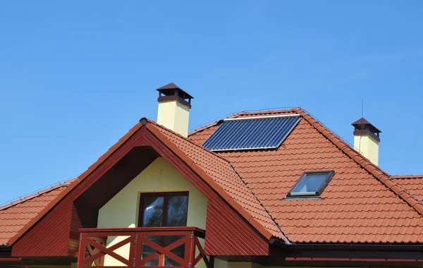 Mavi gökyüzü karşı yeni evin çatısında Isıtma güneş enerjili su paneli. — Stok fotoğraf