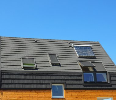 Enerji tasarrufu kavramlar yeni enerji verimliliği çatı tasarım bina. Modern tepe, dormers, asfalt fayans ve güneş enerjili su ısıtma paneli.