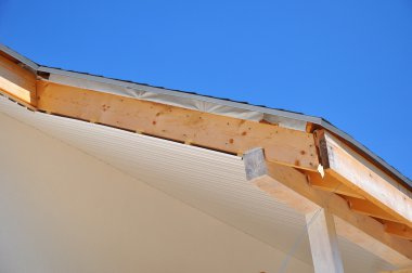 Corner of house with eaves, wooden beams. Install soffits agains blue sky clipart