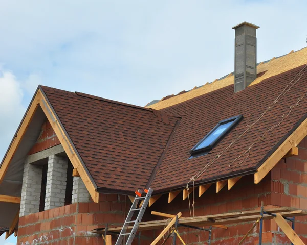 Dach und Bau eines neuen Hauses mit modularem Schornstein, Bitumenziegel, Dachfenster und Traufe. — Stockfoto