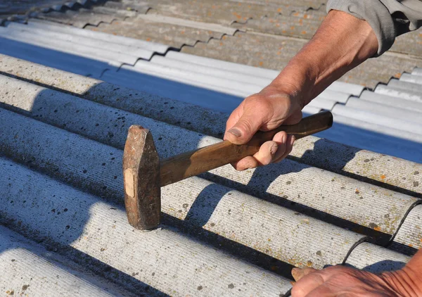 Roofer instala telhas de telhado de amianto - close-up em mãos. Reparação de telhados amianto perigoso telhas do telhado velho . — Fotografia de Stock