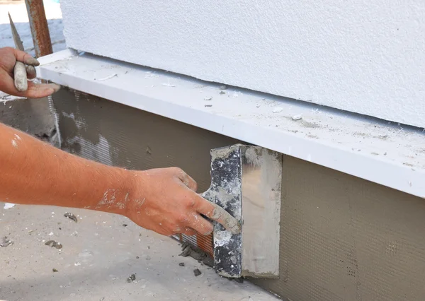 La mano del hombre enyesando un aislamiento de pared con paleta . — Foto de Stock