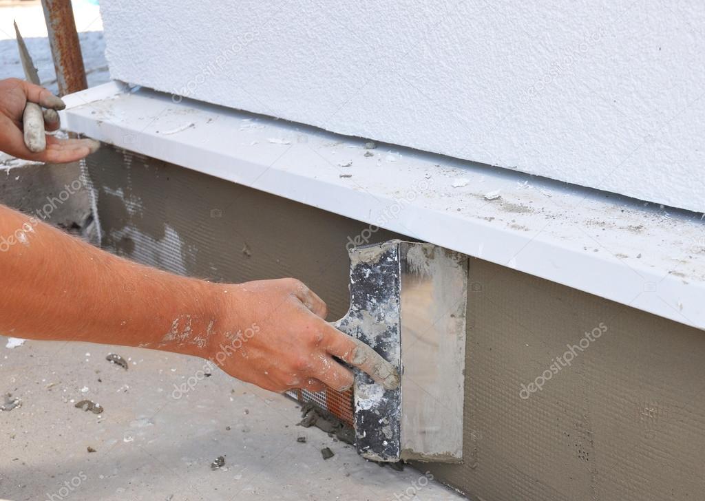 Man's hand plastering a wall insulation with trowel.