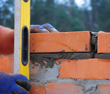Onun duvar kontrol etmek için bir düzey kullanarak bir Duvarcı