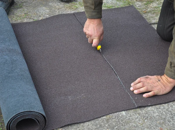 Roofer skärande rulle takpapp eller bitumen under tätskikt — Stockfoto